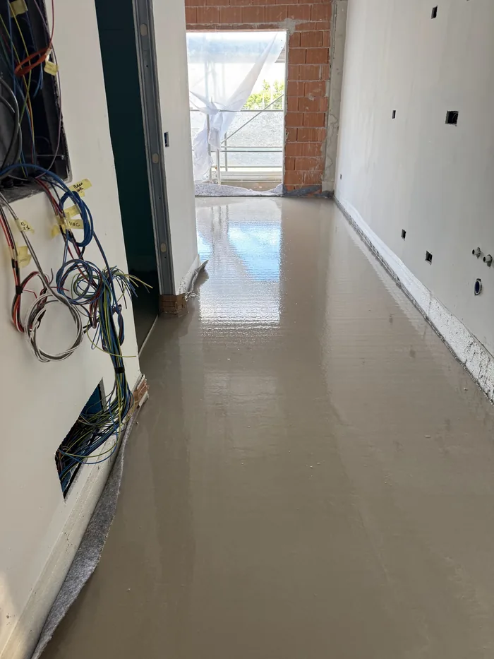 Autolivellante appena colato in un corridoio: la superficie riflette la luce delle finestre