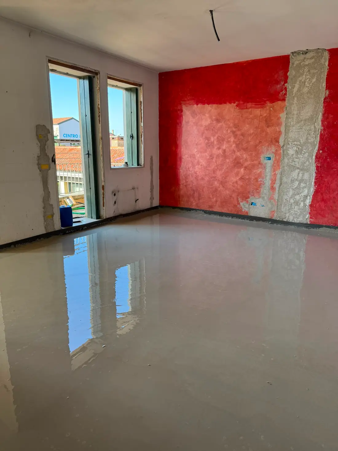 Massetto autolivellante appena colato: la superficie riflette le finestre